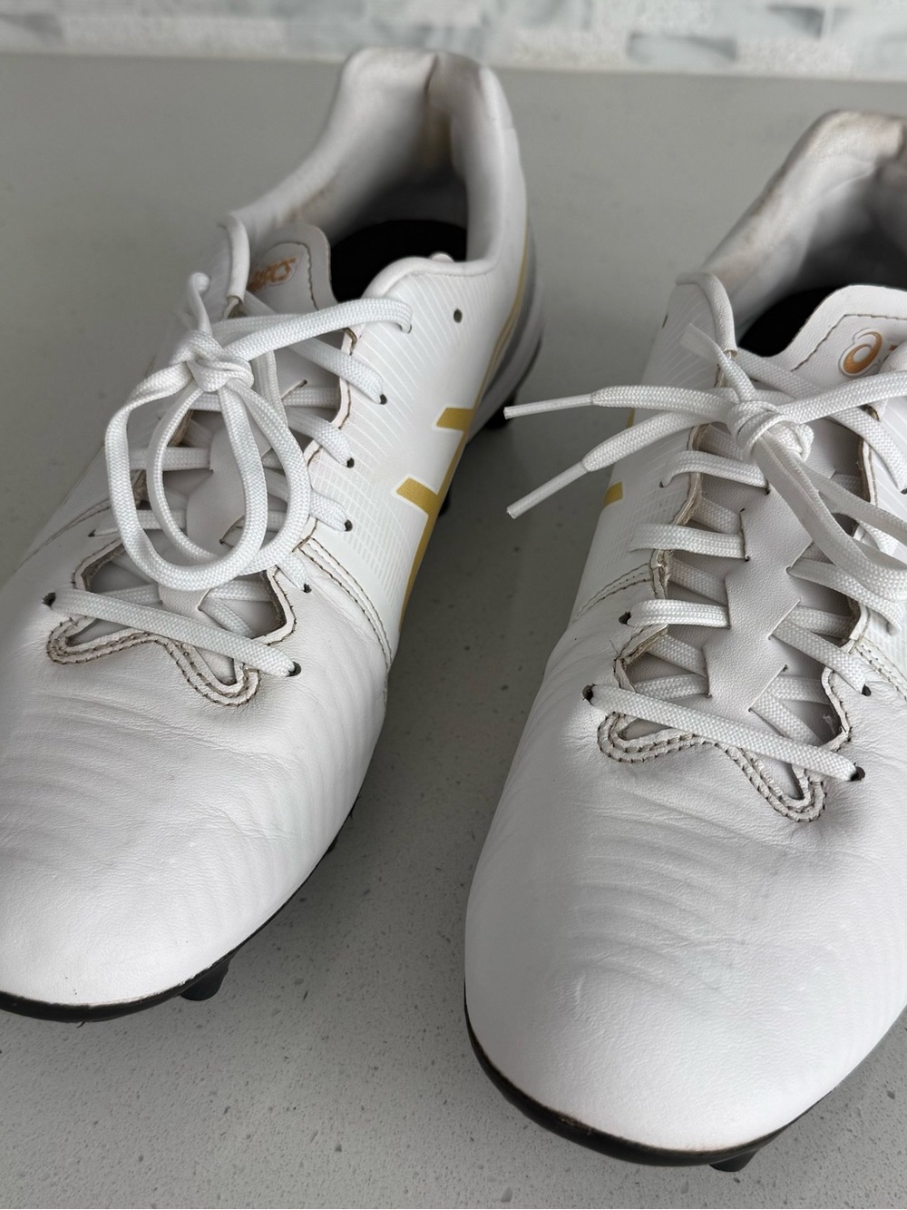 ASICS White Athletic Cleats with Gold Accents